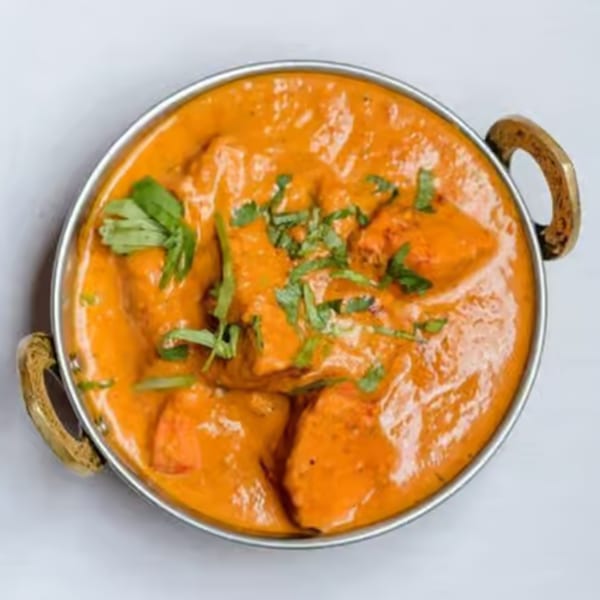 Curry Mantra's chicken tikka masala, a vibrant orange curry with chicken pieces, garnished with fresh cilantro.