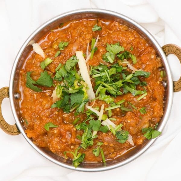 Curry Mantra's Indian eggplant bharta, a smoky mashed eggplant dish, garnished with fresh cilantro and ginger.